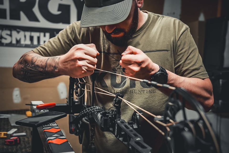 Bow technician working on a compound bow at the Bergy Bowsmith bow press